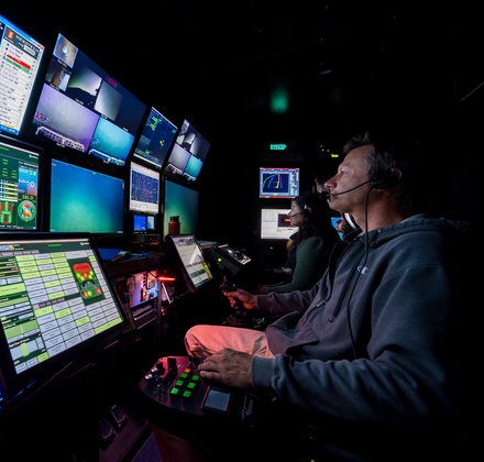 Monterey Bay Aquarium Research Institute (MBARI) and Monterey Bay Aquarium staff on a research trip aboard the Rachel Carson, viewing and analyzing multiple screens of data and video in a darkened room