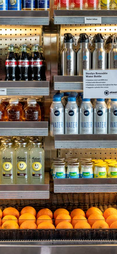 Refrigerated display case stocked with beverages, reusable water bottles, and fresh fruit at the Aquarium