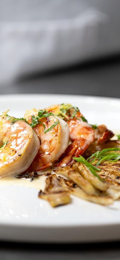 Chefs behind the scenes in a kitchen preparing shrimp, fish, and seafood dishes at Monterey Bay Aquarium
